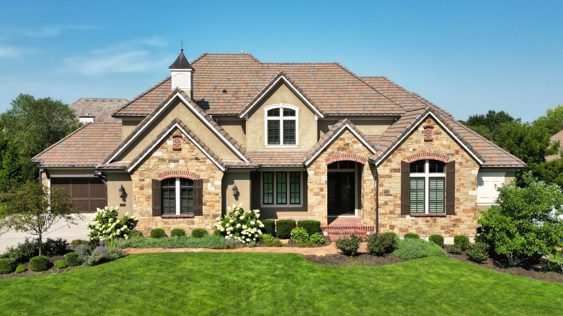 Exterior photo of tan and stone home with blue sky