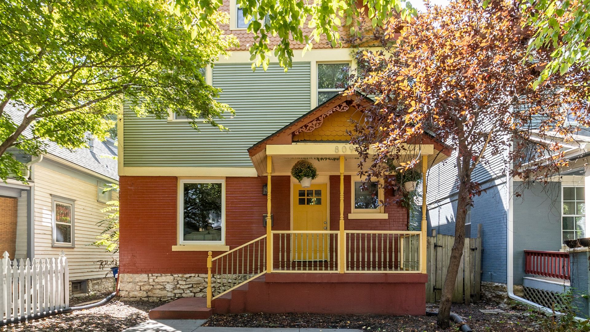 Red and green shirtwaist home with yellow front door.