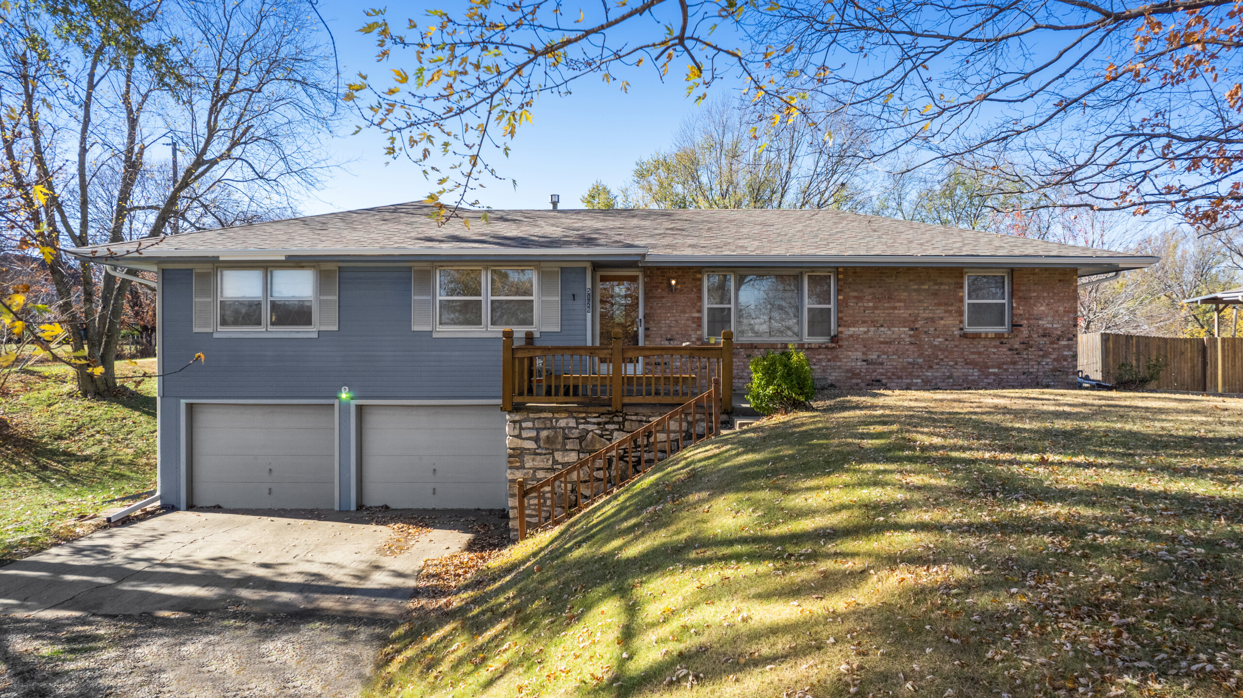 Front view of home with two car garage and is painted half blue and half brick.