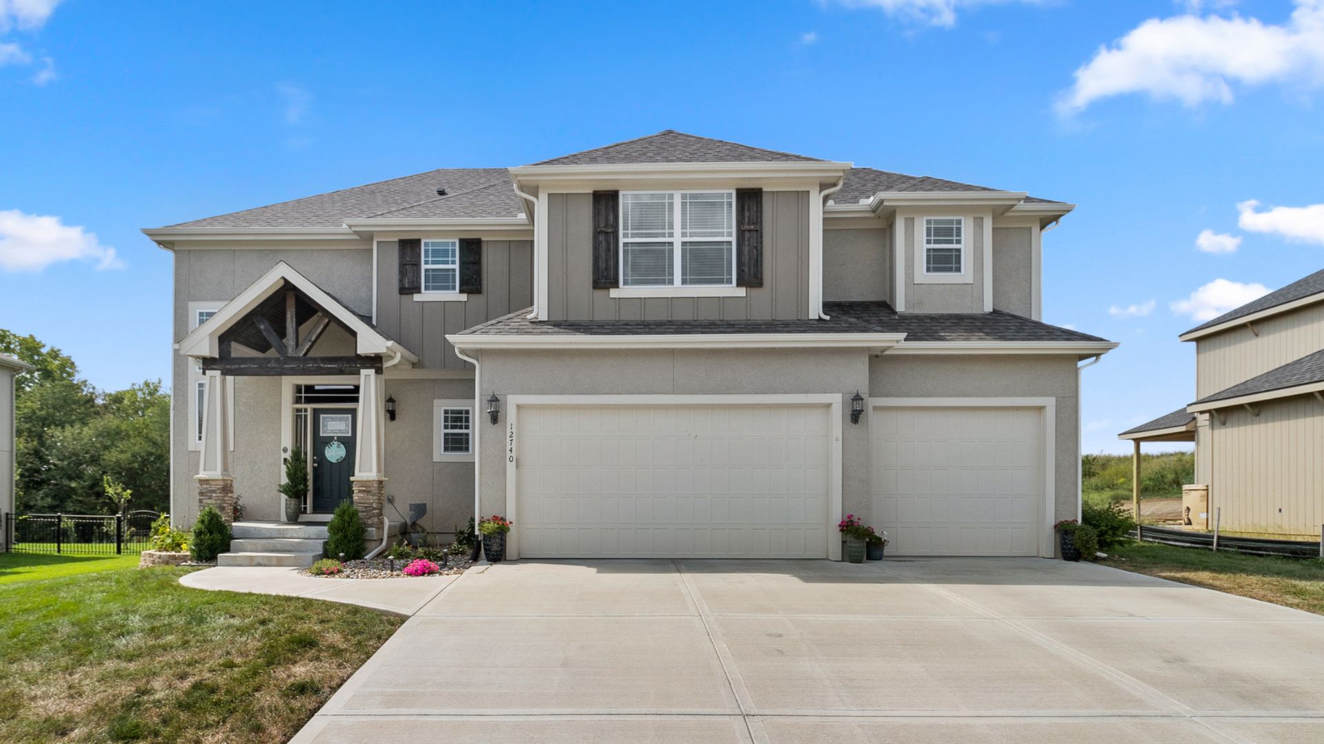 Front photo of gray home with 3 care garage and large driveway.