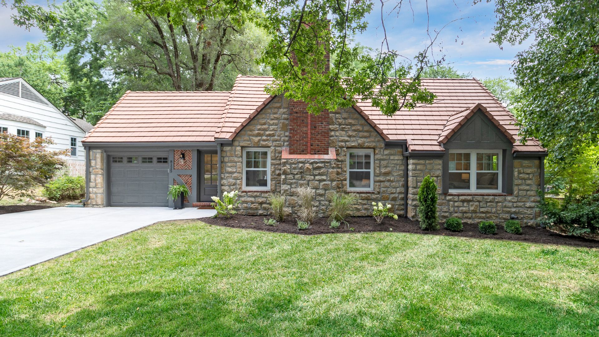 Stone and brick home with well manicured, green lawn.