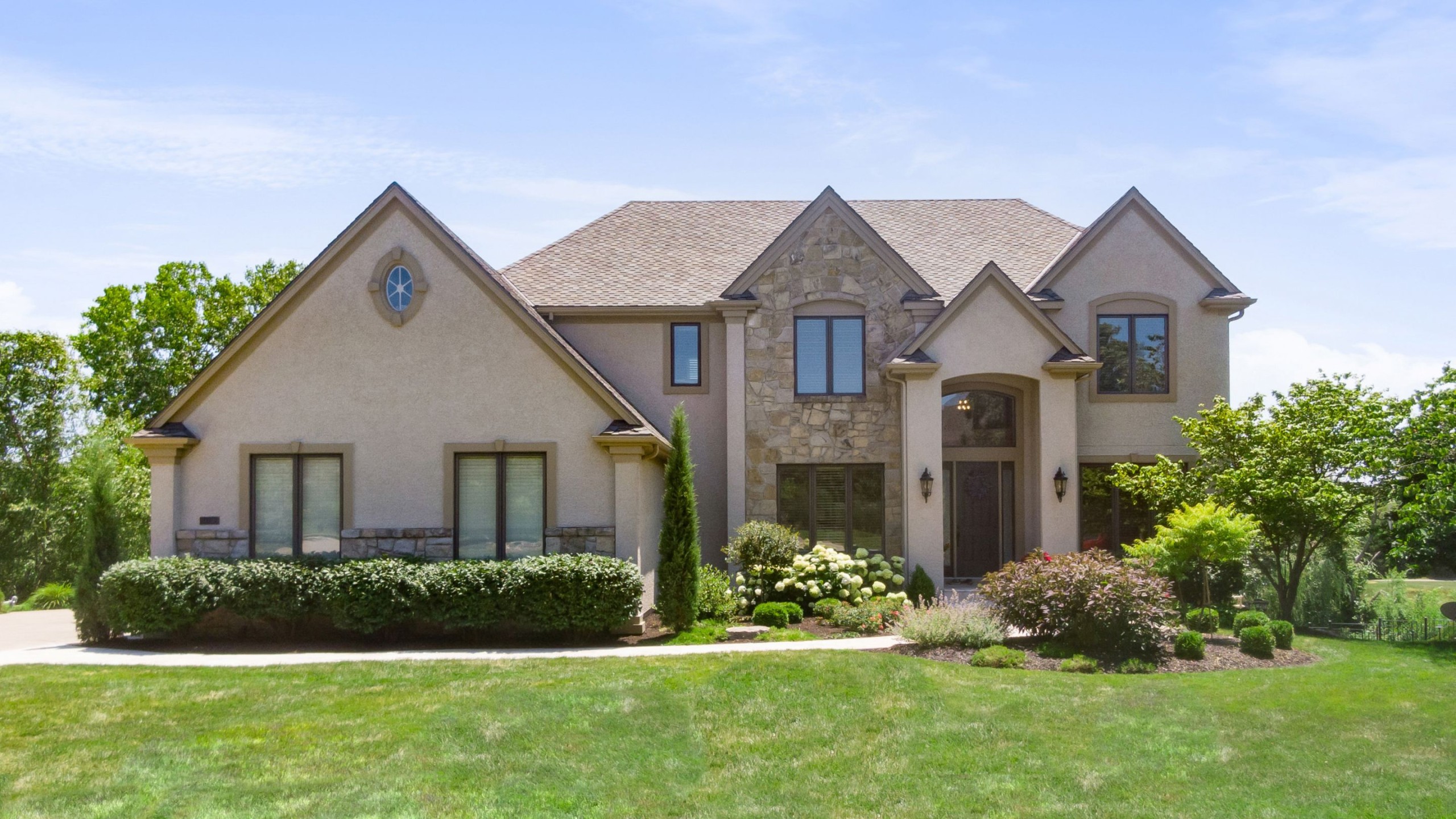 Tan home with stone and lush landscaping