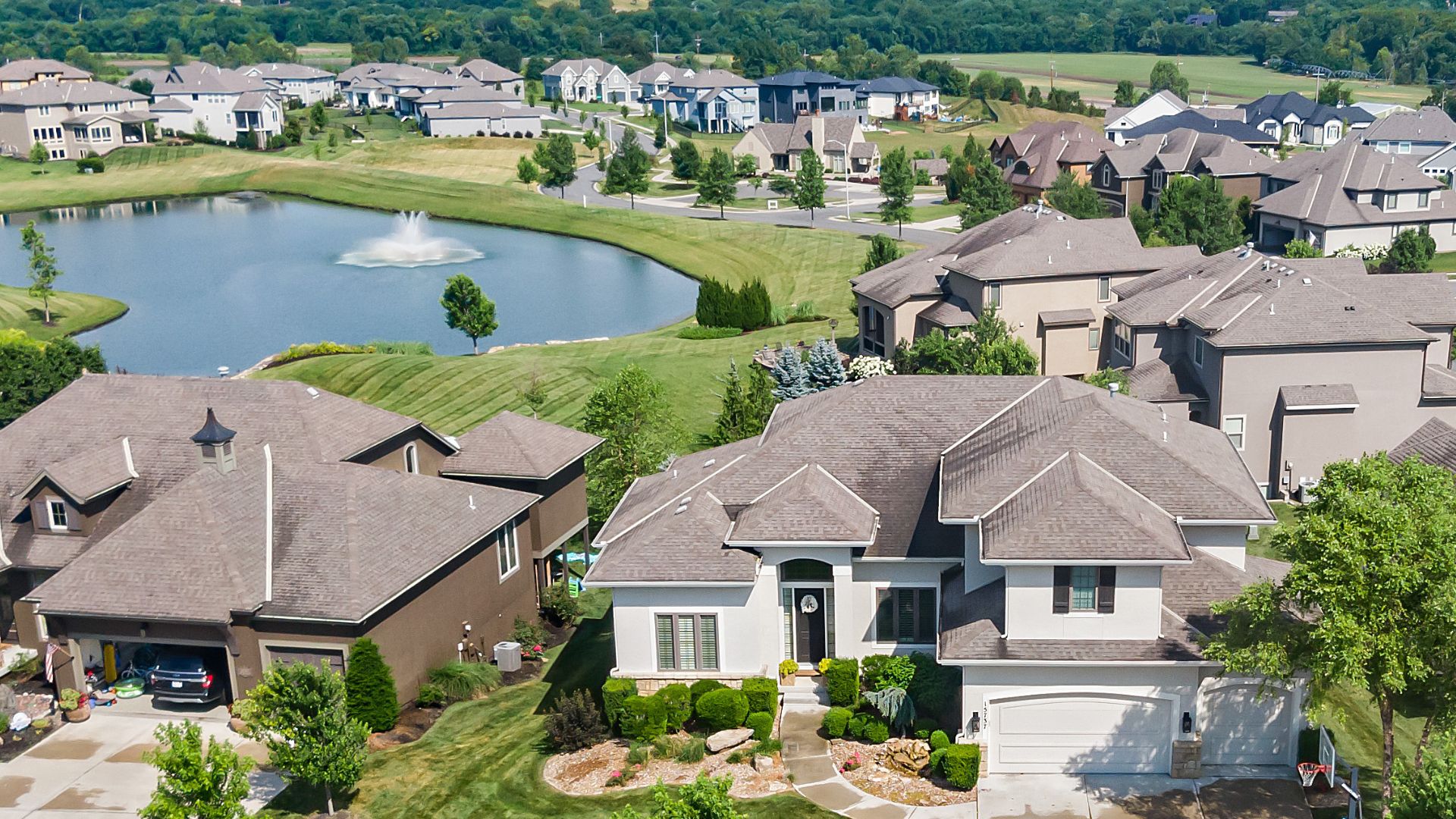 Drone shot of a home backing to a large pond with fountain.