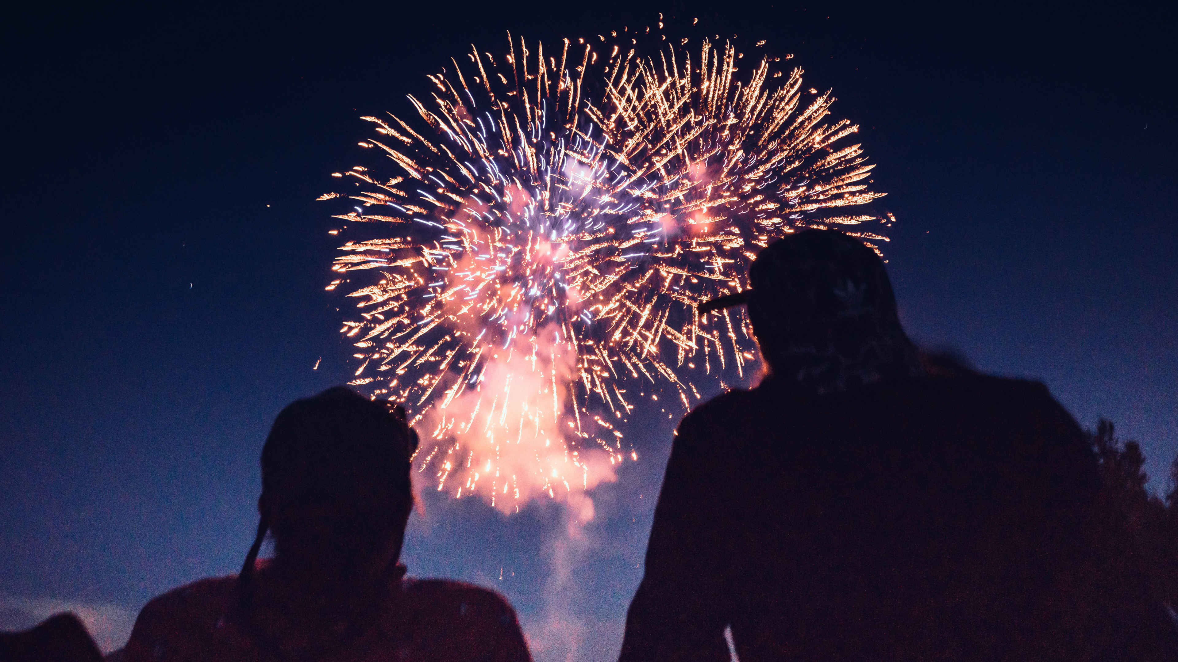 Silhouette of two people watching fireworks in the sky